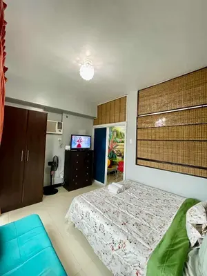 a bedroom with a bed and a television in it at Tropical unit in Manila