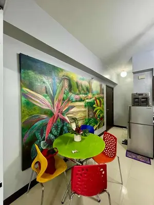a dining room with a table and chairs and a painting at Tropical unit in Manila