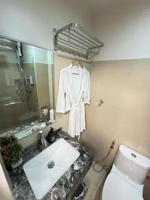 a bathroom with a sink and a white robe on a mirror at The Horizon Suite by Crib2GO in Manila