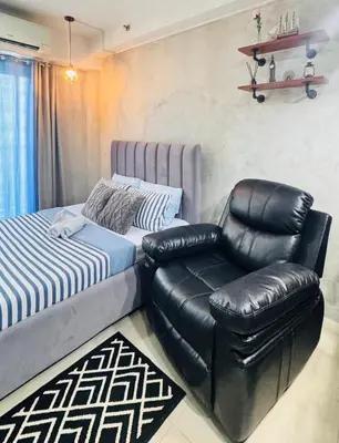 a bedroom with a bed and a leather chair at GreySky Studio in Manila