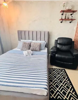 a bed and a chair in a room at GreySky Studio in Manila