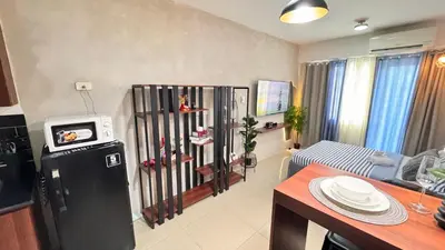 a living room with a small television and a kitchen at GreySky Studio in Manila