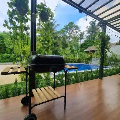 a grill on a table with a bench and a pool at The Zentuary - House with pool in Amadeo