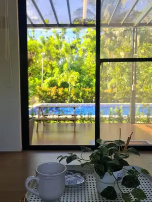 a table with a coffee cup and a plant in front of a window at The Zentuary - House with pool in Amadeo