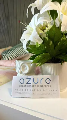 a vase of flowers sitting on a table with a book at Azure Urban Resort Residences, 1BR Santorini 18th floor in Manila