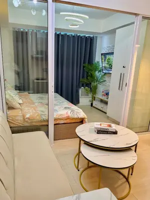a living room with a bed and a table at Azure Parañaque, 1BR Bahamas 15th floor in Manila