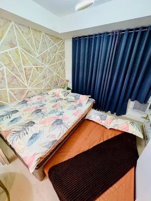 a bedroom with a bed and a blue curtain at Azure Parañaque, 1BR Bahamas 15th floor in Manila
