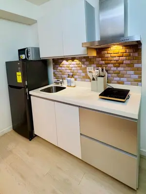 a kitchen with a sink and a black refrigerator at Azure Parañaque, 1BR Bahamas 15th floor in Manila