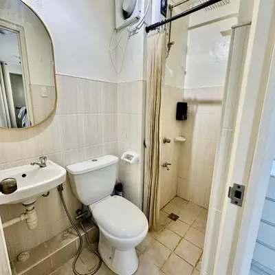 a bathroom with a toilet and a sink and a mirror at ComfyCondo near Enchanted Kingdom in Santa Rosa