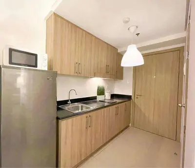 a kitchen with wooden cabinets and a stainless steel refrigerator at Wowstaycation in Manila