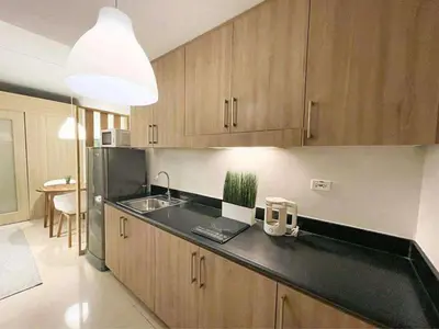 a kitchen with wooden cabinets and a sink and a light at Wowstaycation in Manila