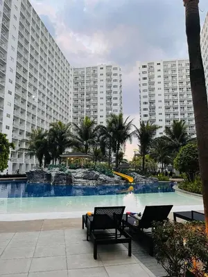 a large swimming pool with two chairs in front of buildings at Wowstaycation in Manila