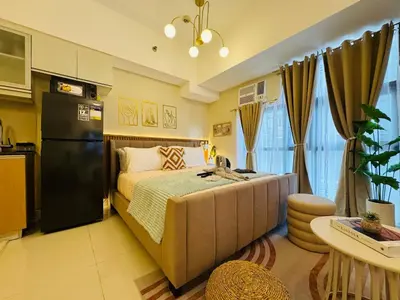 a small bedroom with a bed and a kitchen at Cozy Studio in Viceroy Near Venice Mall in Manila
