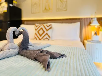 two towel swans sitting on top of a bed at Cozy Studio in Viceroy Near Venice Mall in Manila