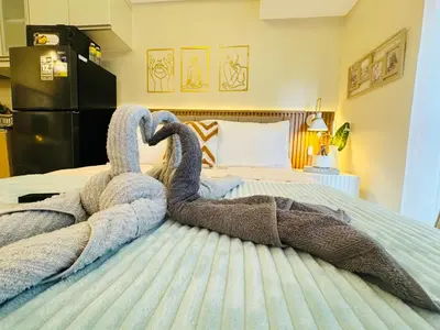 two towels shaped like swans sitting on a bed at Cozy Studio in Viceroy Near Venice Mall in Manila