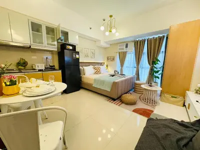 a room with a bed and a table and a kitchen at Staycation in viceroy mckinley near venice grand canal in Manila
