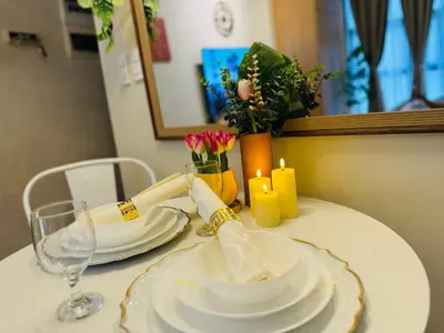 a table with white plates and candles and flowers at Staycation in viceroy mckinley near venice grand canal in Manila