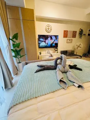 a bedroom with a large bed with a towel on it at Staycation in viceroy mckinley near venice grand canal in Manila