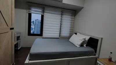 a bedroom with a bed with a window with blinds at 1 Bedroom Cozy and Relaxing Place in Manila