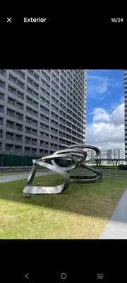 a metal bench sitting in the grass in a city at 1 Bedroom unit in Fame Residence in Manila