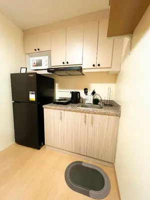 a kitchen with a sink and a black refrigerator at Jungle Hostel 1062 in Manila