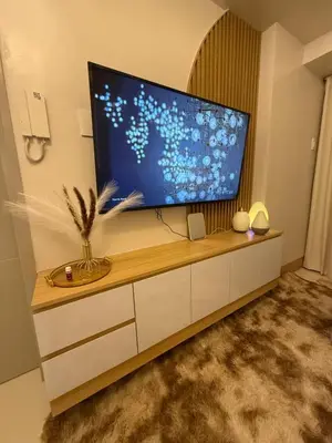 a living room with a large flat screen tv on a cabinet at Glamorous SMDC Shore 3, 5 Star Rate BnB-Wifi-Netflix in Manila