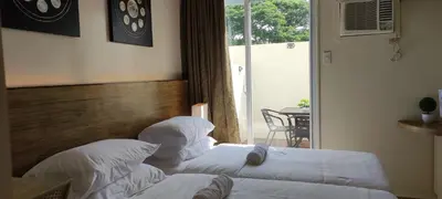 a bedroom with two beds with white sheets and a window at Cozy Suite with Private Patio near Nuvali in Silang