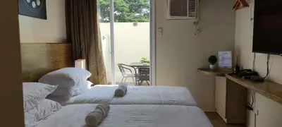 two beds in a hotel room with a balcony at Cozy Suite with Private Patio near Nuvali in Silang