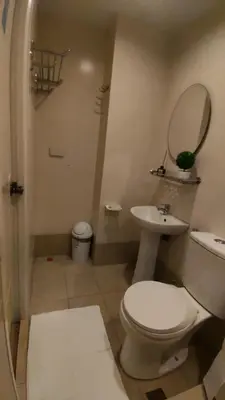 a bathroom with a toilet and a sink and a mirror at Cozy Suite with Private Patio near Nuvali in Silang