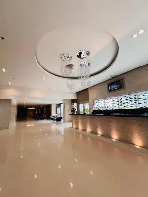 a hotel lobby with a reception desk and chandelier at Sea Residence MOA - Paul Condotel in Manila