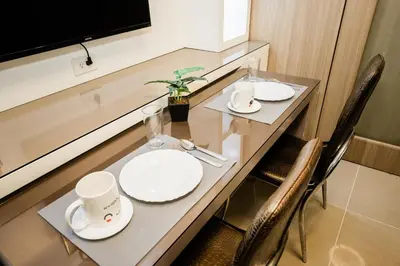 a dining table with white plates and mugs on it at Family Suite near MOA in Manila