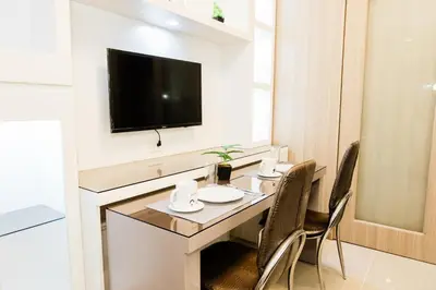 a dining room table with chairs and a tv on a wall at Family Suite near MOA in Manila