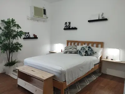 a bedroom with a bed and two lamps and a plant at Delet TEA in Manila