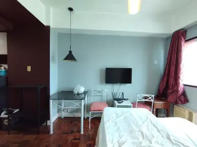 a bedroom with a bed and a desk and a tv at Delet CITADEL in Manila