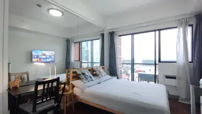 a bedroom with a bed and a desk and windows at Delet CITADEL in Manila
