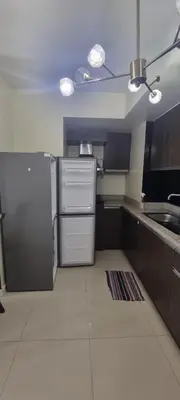 a small kitchen with a refrigerator and a sink at Rikki Staycation in Manila