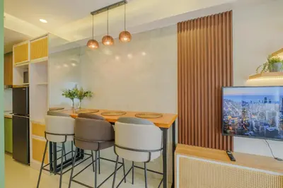 a kitchen with a bar with stools and a tv at Coasis at SMDC Coast Residences in Manila