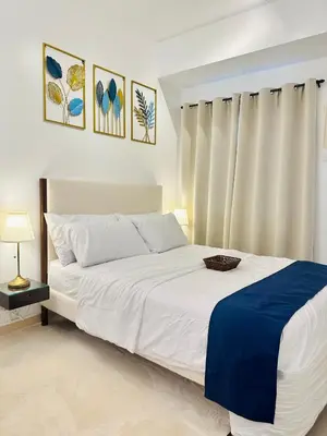 a bedroom with a white bed with a blue blanket at Micasa at Green 2 Residences in Dasmariñas