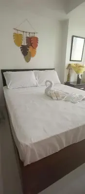 a bed with white sheets and a table with a lamp at Casa Crisav Staycation place at AZURE in Manila