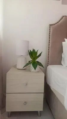 a nightstand with a plant on it next to a bed at Casa Crisav Staycation place at AZURE in Manila