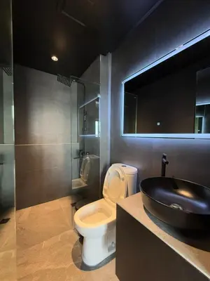 a bathroom with a toilet and a black sink at Malate Bayview Mansion 37M in Manila