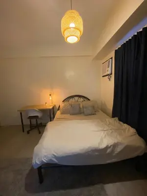 a bedroom with a bed and a table and a chandelier at The Mood Shift in Manila