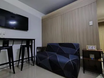 a living room with a blue chair and a television at Shore Residences - 2 Bedroom Pool View Near Moa in Manila