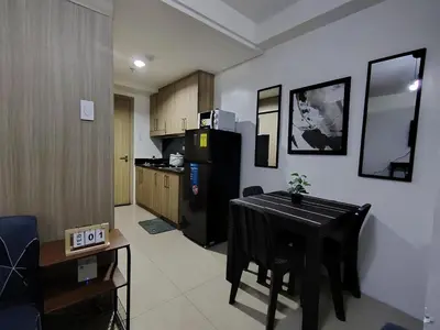 a kitchen with a table and a black refrigerator at Shore Residences - 2 Bedroom Pool View Near Moa in Manila