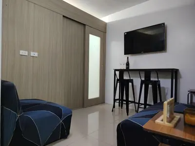 a living room with a television and a table and chairs at Shore Residences - 2 Bedroom Pool View Near Moa in Manila