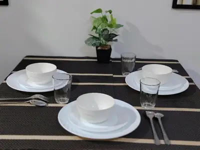 a table with white plates and glasses on it at Shore Residences - 2 Bedroom Pool View Near Moa in Manila