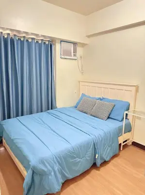 a bedroom with a bed with blue sheets and a window at Brixton place 2815 Weston tower in Manila