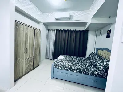 a bedroom with a blue bed in a room at Crisean Highrise Condo - 100 West makati in Manila