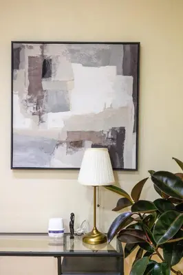 a lamp on a desk with a painting on the wall at Forbeswood Heights 1Br with Garden view in Manila