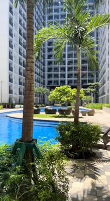 a swimming pool with two palm trees and buildings at Cozy Vibes near MOA & NAIA AIRPORT with NETFLIX,MINIVIDEOKE,BOARDGAMES-DUXE4 in Manila